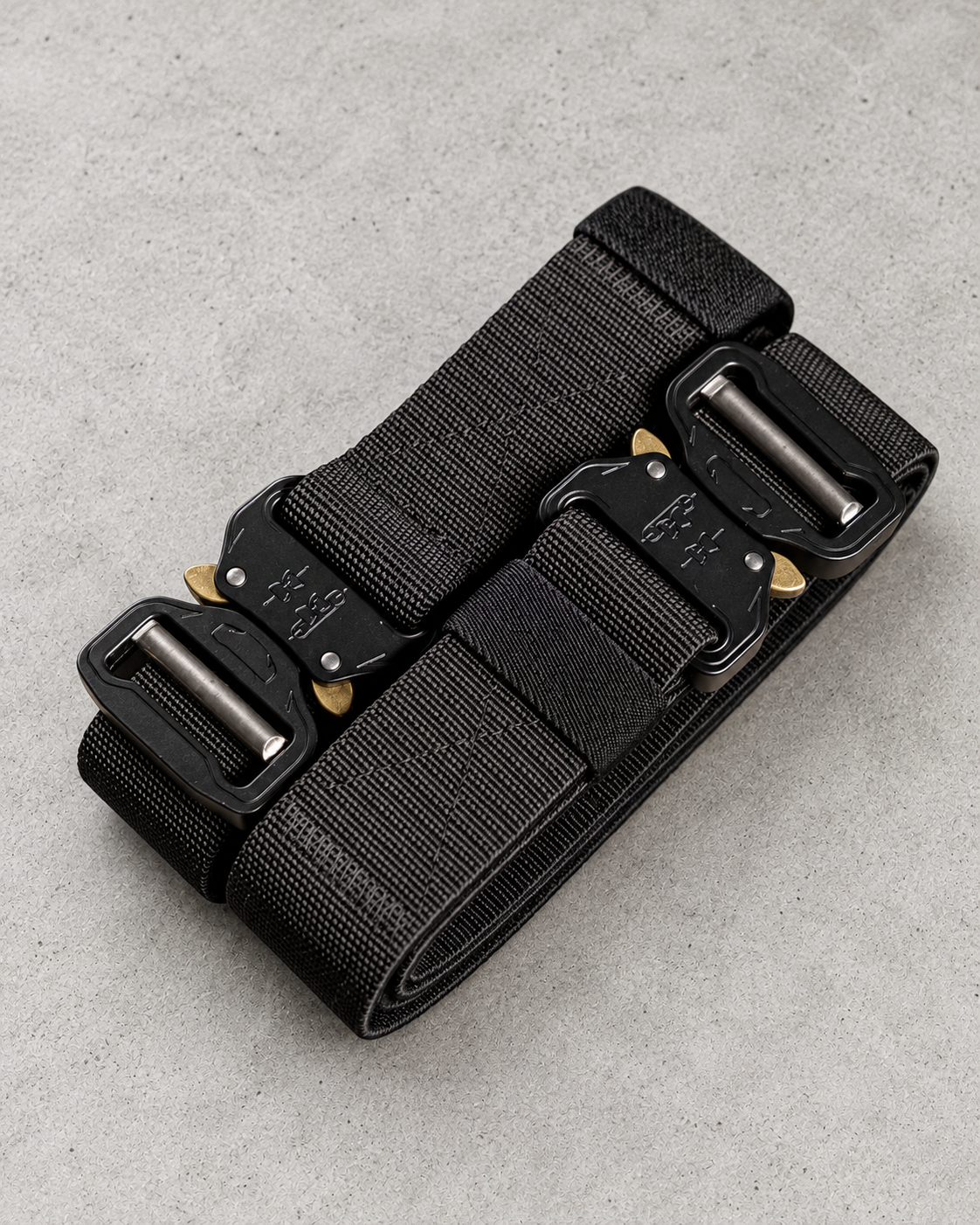 Ultra Belt with black woven webbing and metal buckle on a light textured background