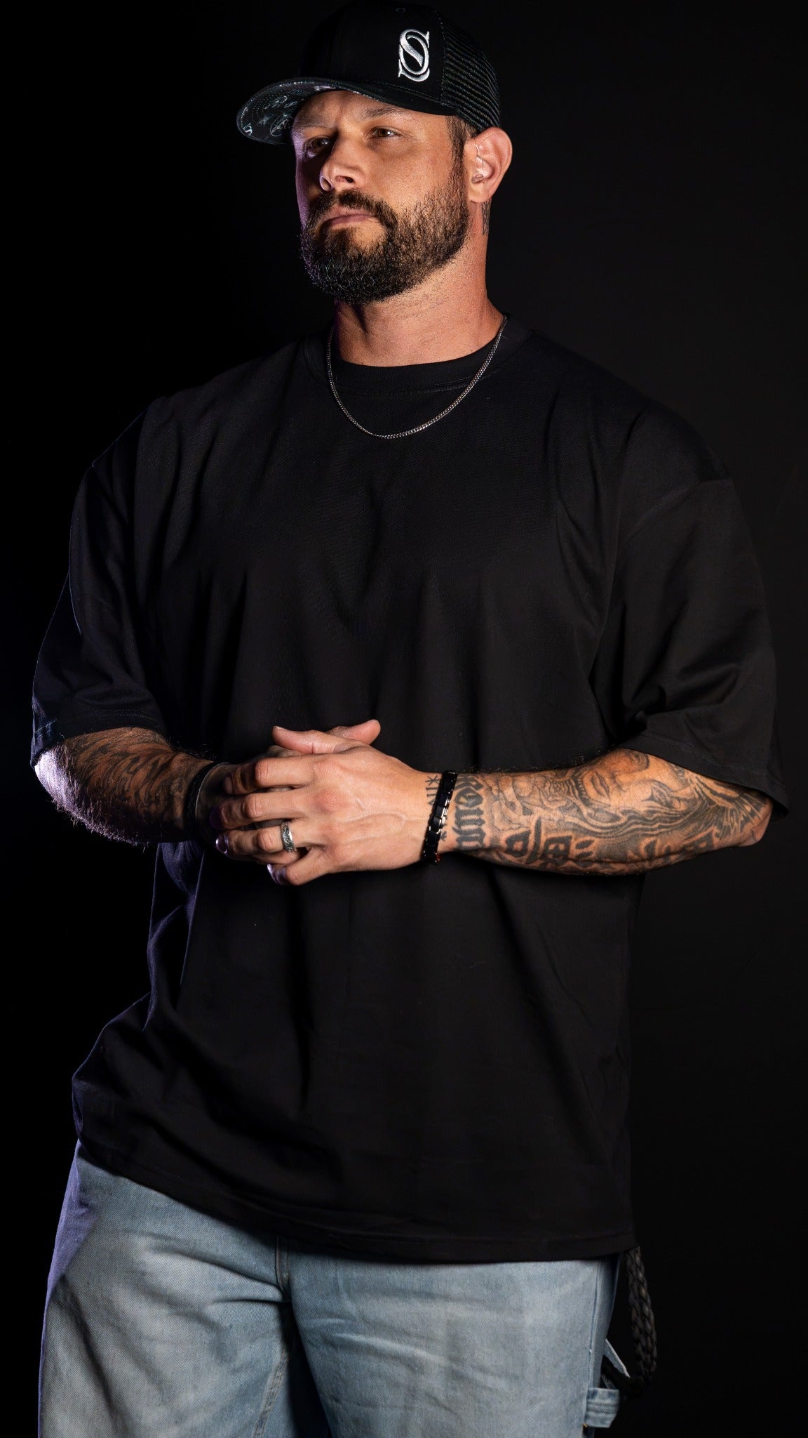 Original front photograph of Guy in an unprinted black drop-shoulder tee, hands held together